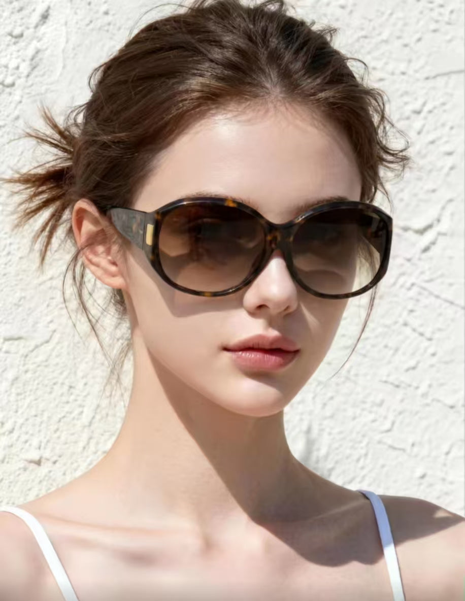 Woman wearing tortoise shell full-rim oversized rounded-square polycarbonate sunglasses, three-quarter portrait